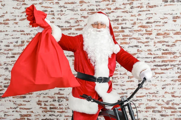 Papai Noel com saco e bicicleta perto da parede de tijolo — Fotografia de Stock