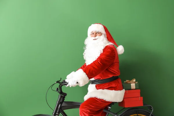 Santa Claus z prezentów świątecznych i rower na tle koloru — Zdjęcie stockowe