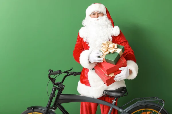Santa Claus z prezentów świątecznych i rower na tle koloru — Zdjęcie stockowe