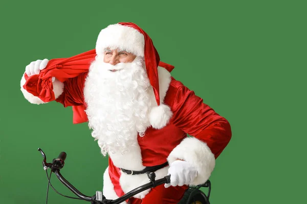 Babbo Natale con borsa in sella bicicletta su sfondo colore — Foto Stock