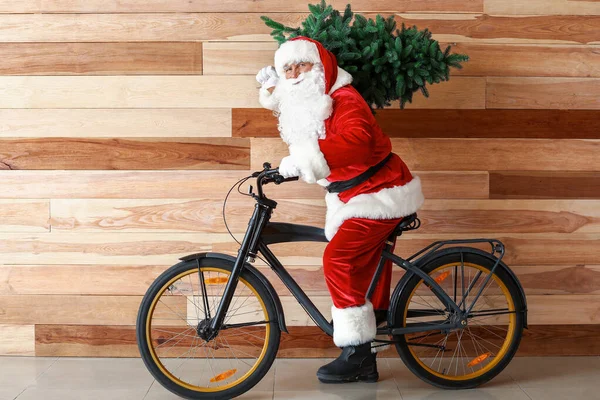 Święty Mikołaj z jodłą i rowerem w pobliżu drewnianej ściany — Zdjęcie stockowe