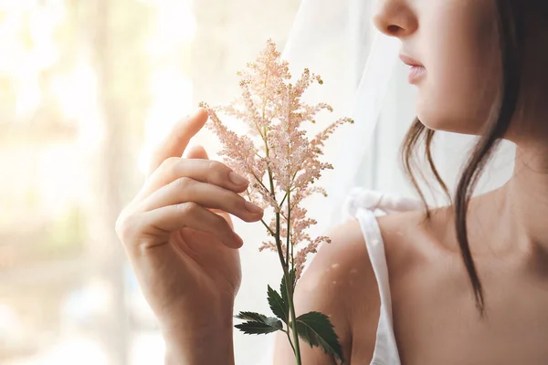 Kvinna med vackra blommor nära fönstret — Stockfoto