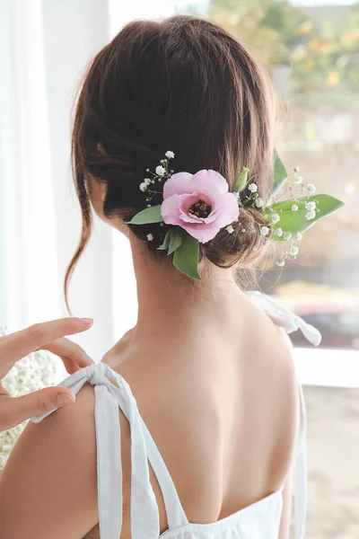 Woman with beautiful flowers in her hair near window — Stock Photo, Image