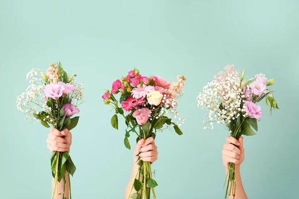 Manos femeninas con ramos de hermosas flores sobre fondo de color — Foto de Stock