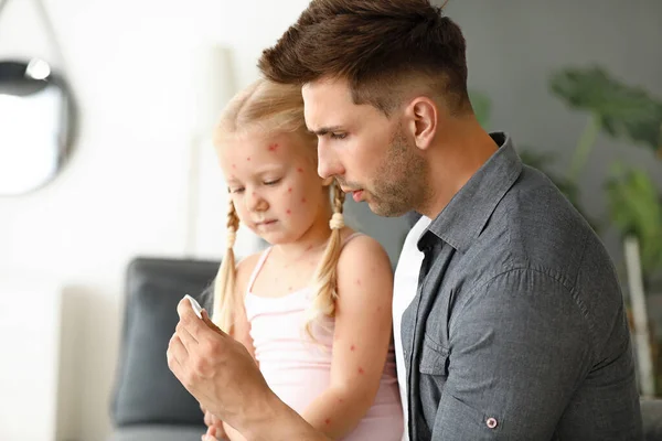 Hombre midiendo la temperatura de su pequeña hija enferma de varicela en casa — Foto de Stock