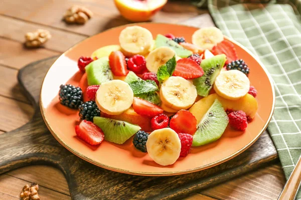 Placa con sabrosa ensalada de frutas en la mesa —  Fotos de Stock