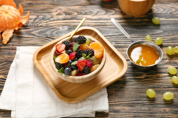 Bowl with tasty fruit salad on wooden table — Stock Photo, Image