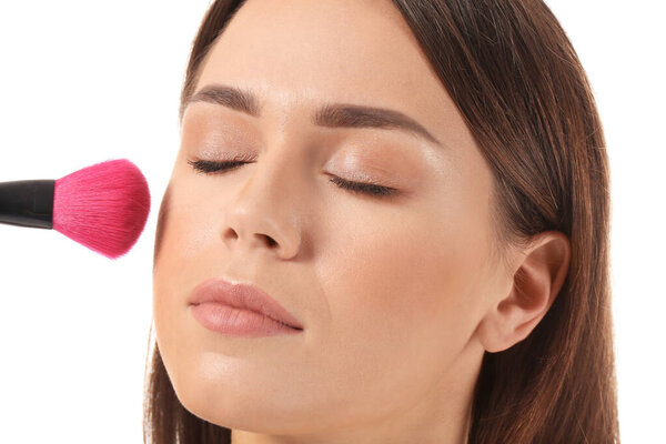 Красивая молодая женщина с кистью макияжа на белом фоне