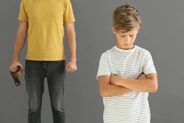 Küçük oğlunu gri arka planda tehdit eden bir adam. Fiziksel ceza kavramı