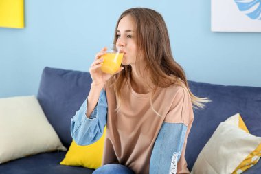 Güzel genç bayan evde portakal suyu içiyor.