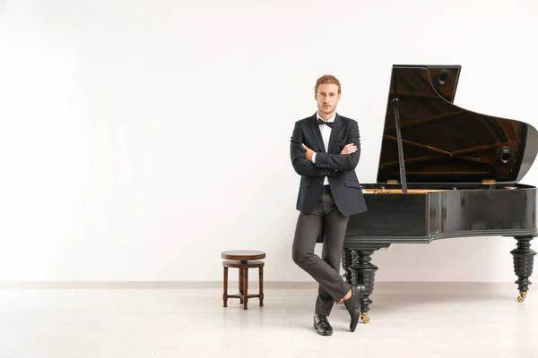 Homem perto de piano de cauda contra parede branca — Fotografia de Stock