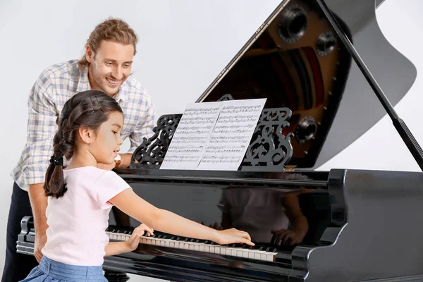 Мужчина учит маленькую девочку играть на пианино — стоковое фото