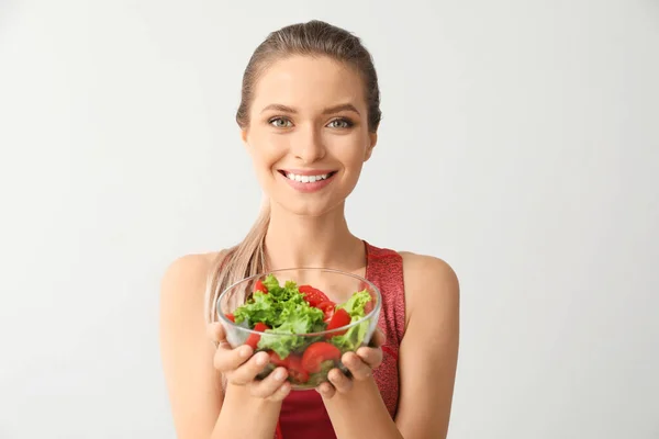 Mulher esportiva com salada de legumes saudável no fundo claro. Conceito de dieta — Fotografia de Stock