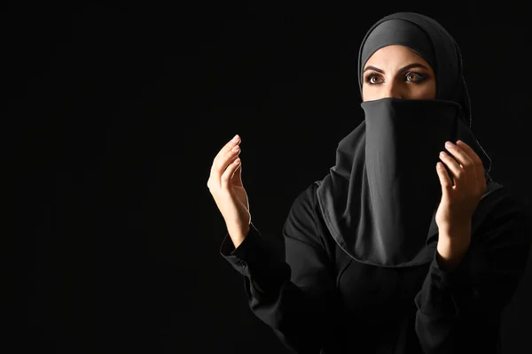 Beautiful Muslim woman praying against dark background — Stock Photo, Image