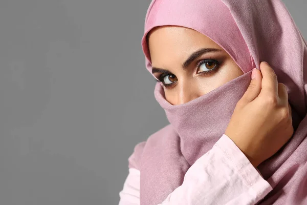 Portrait of beautiful Muslim woman on grey background — Stock Photo, Image