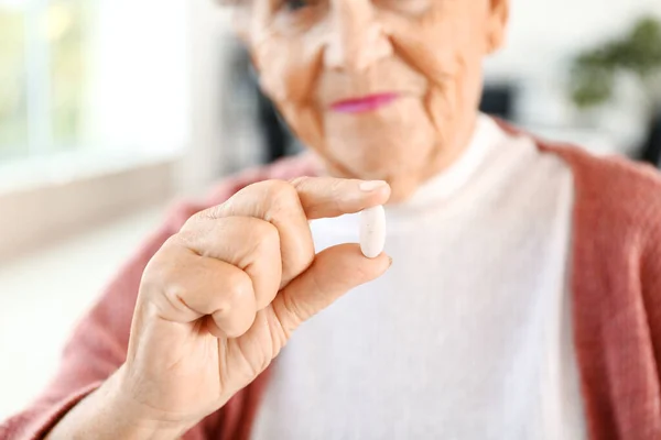 Elderly woman taking medicine at home, closeup