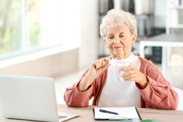 Elderly woman taking medicine at home — Stock Photo, Image