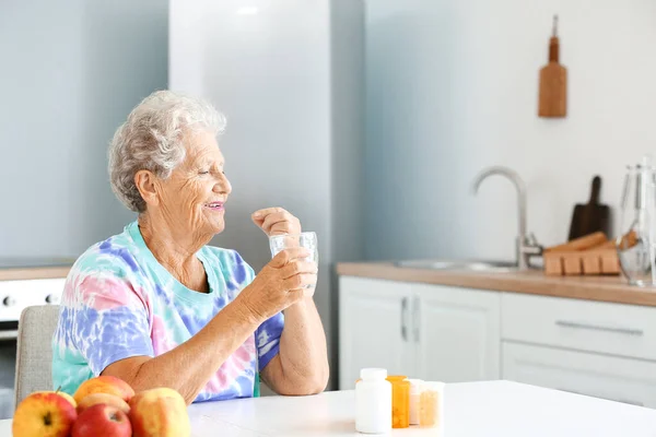 Ältere Frau nimmt Medikamente zu Hause ein — Stockfoto