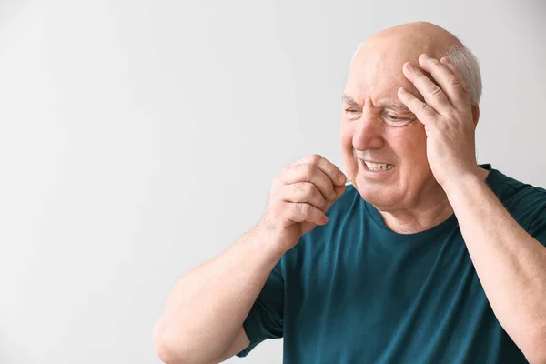 Hombre de edad avanzada que toma medicamentos sobre fondo claro — Foto de Stock