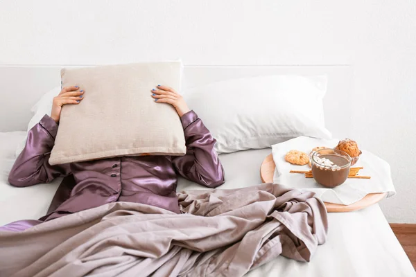 Sleepy woman with pillow lying in bed near tasty breakfast — Stock Photo, Image