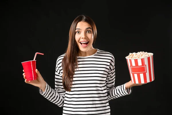 Surprised woman with popcorn and soda drink on dark background — Stock Photo, Image