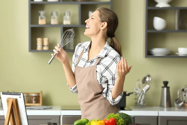Schöne junge Frau singt beim Kochen in der Küche — Stockfoto