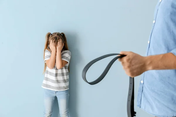 Een man die zijn dochtertje bedreigt tegen een kleurrijke achtergrond. Fysieke straffen — Stockfoto