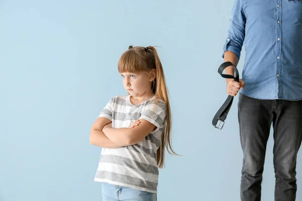 Hombre amenazando a su pequeña hija contra el fondo de color. Concepto de castigo físico —  Fotos de Stock