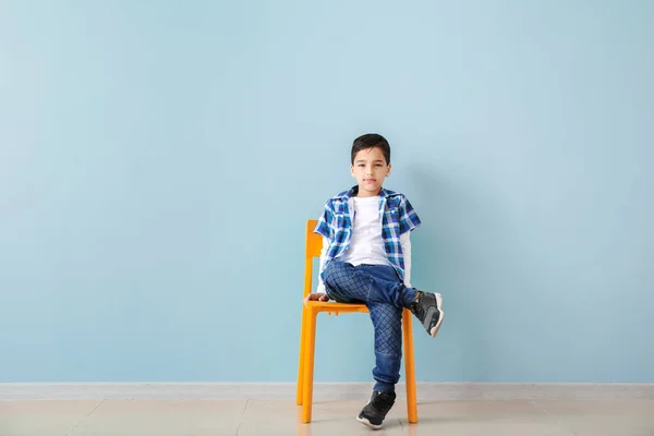 색깔 벽에 기대어 의자에 앉아 있는 귀여운 유행하는 소년 — 스톡 사진