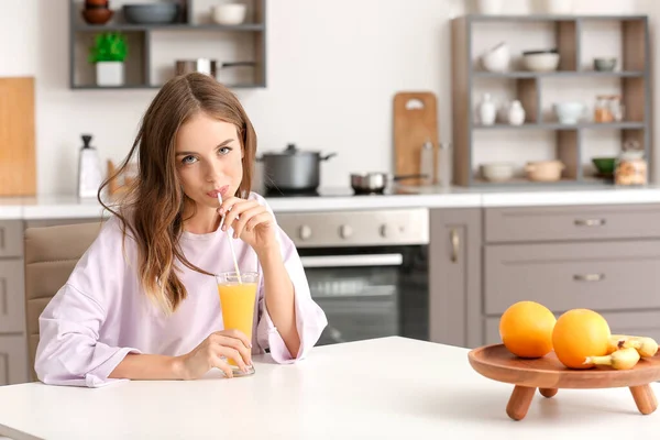 Belle jeune femme buvant du jus d'orange dans la cuisine — Photo