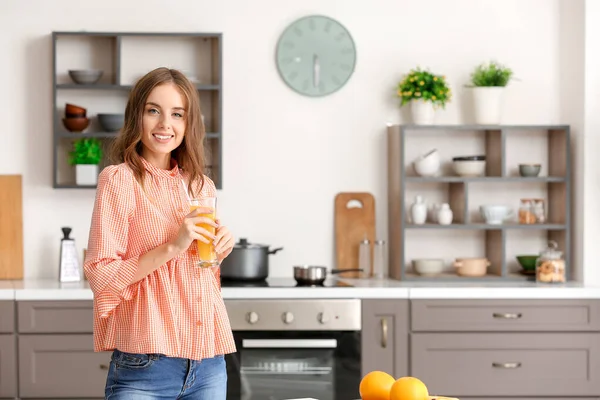Mulher bonita bebendo suco de laranja na cozinha — Fotografia de Stock