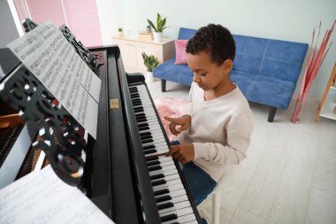 Küçük Afro-Amerikalı çocuk evde piyano çalıyor.