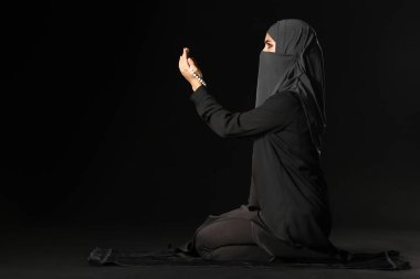 Güzel Müslüman kadın karanlık arka plan için dua ediyor