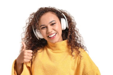 Güzel bir Afro-Amerikalı kadın beyaz arka planda müzik dinlerken başparmağını kaldırıyor.