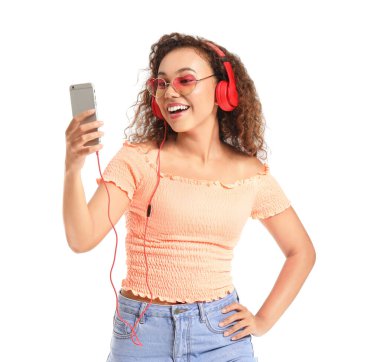 Güzel Afro-Amerikalı kadın beyaz arka planda müzik dinliyor.