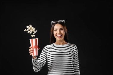 Genç bir kadın arka planda patlamış mısır atıyor.