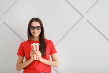 Gri arka planda patlamış mısırı olan genç bir kadın.