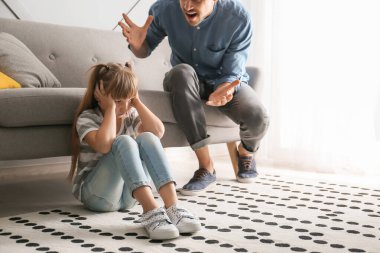 Kızgın baba küçük kızını evde azarlıyor.