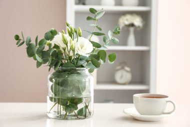 Güzel çiçekli vazo ve masadaki bir fincan çay.