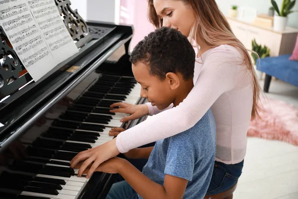 Kvinna undervisning Little Afro-American boy att spela piano hemma — Stockfoto