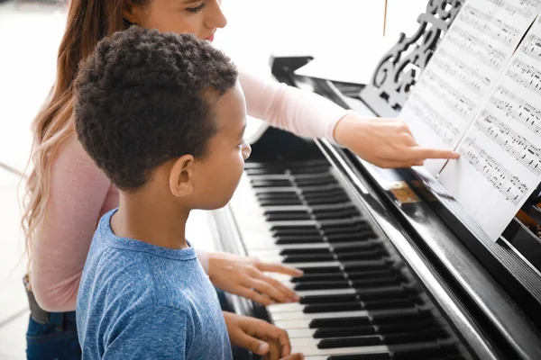 Woman teaching little African-American boy to play piano at home — Stock Photo, Image