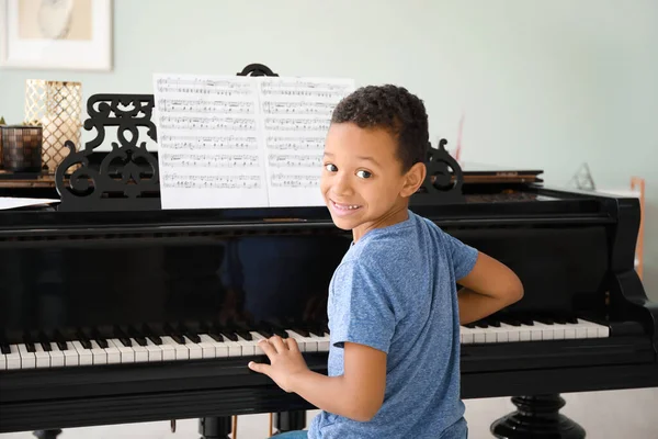 Little African-American boy playing grand piano at home — Stock Photo, Image