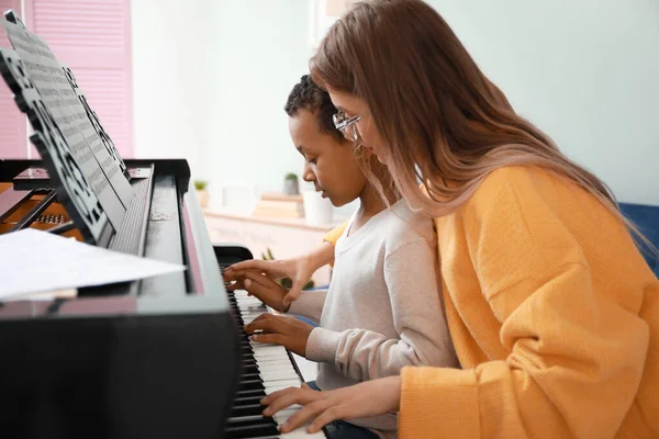 Femme enseignant au petit garçon afro-américain à jouer du piano à la maison — Photo