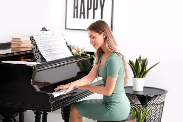 Young woman playing grand piano at home — Stock Photo, Image