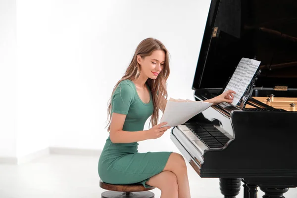 Jeune femme avec feuilles de notes au piano à queue — Photo