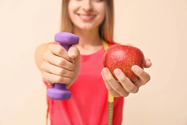 Sportliche Frau mit Hantel und Apfel auf hellem Hintergrund, Nahaufnahme. Ernährungskonzept — Stockfoto