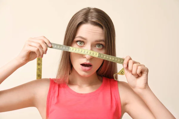 Shocked woman with measuring tape on light background. Diet concept — Stock Photo, Image