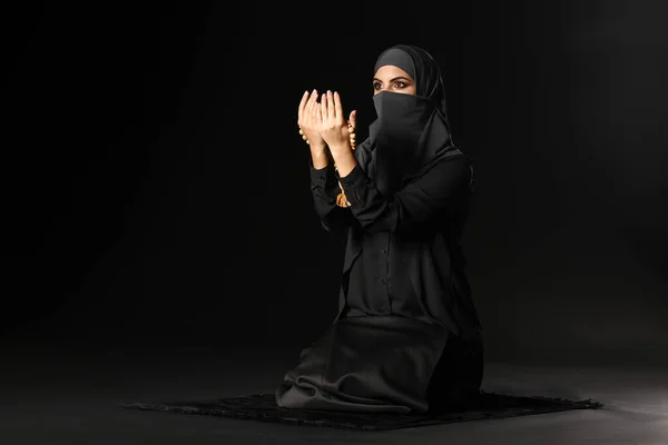 Mulher muçulmana bonita orando contra fundo escuro — Fotografia de Stock