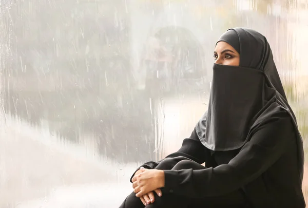 Portrait of beautiful Muslim woman near window on rainy day — Stock Photo, Image