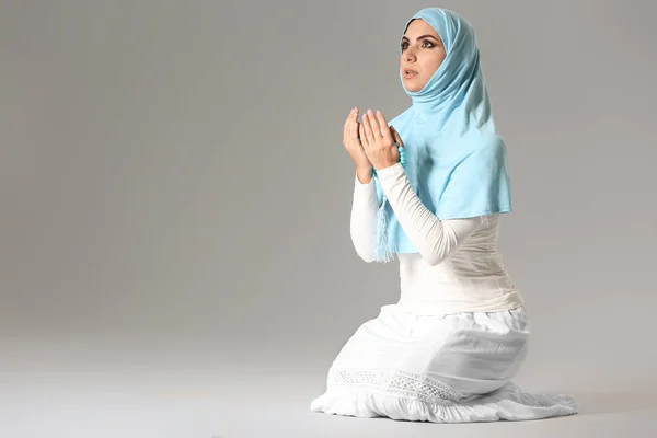 Praying Muslim woman on grey background — Stock Photo, Image